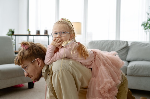 Pai carregando filha fofa nas costas se divertindo em casa