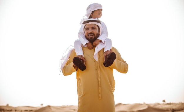 Pai carregando filho no ombro no deserto