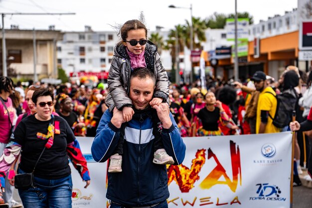 Pai carregando uma criança em seus ombros em um carnaval festivo Carnaval de Montpellier