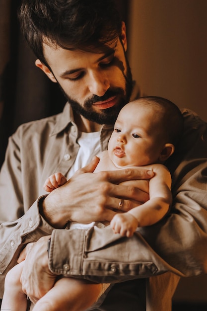 Pai caucasiano beijando bebê recém-nascido Pai segurando filho filha de balanço nas mãos