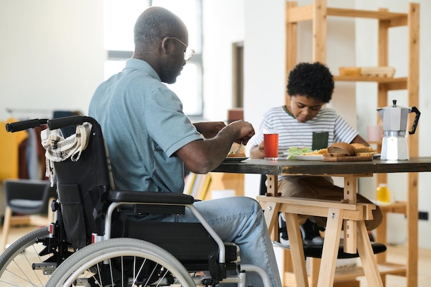 Pai com deficiência tomando café da manhã com seu filho