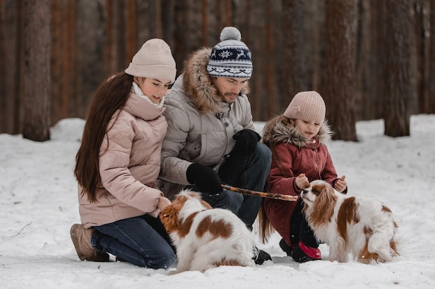 Pai com filhas e cães andam e brincam no passatempo familiar da floresta de inverno