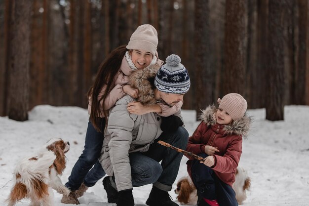 Pai com filhas e cães andam e brincam no passatempo familiar da floresta de inverno