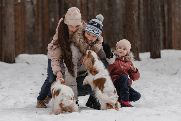 Pai com filhas e cães andam e brincam no passatempo familiar da floresta de inverno