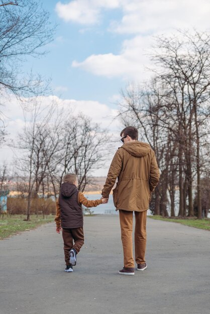 Pai com filho andando pelo parque de mãos dadas