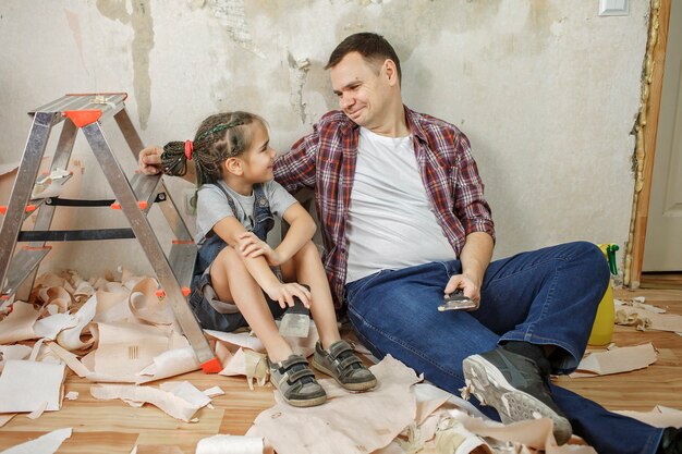 Pai com filho consertando quarto juntos e papel de parede imutável juntos