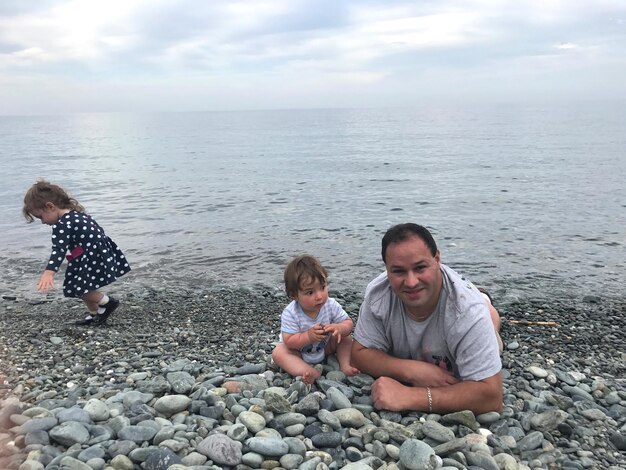 Foto pai com filho e filha na praia contra o céu