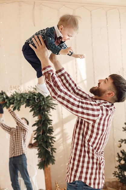 Pai com filho em pé na sala com atmosfera de Natal