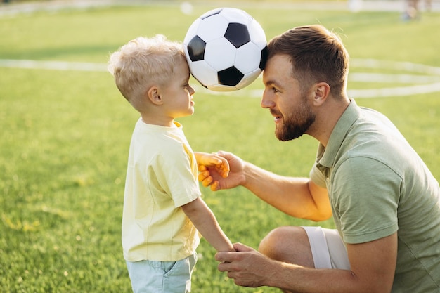 Foto pai com filho jogando futebol no campo de futebol