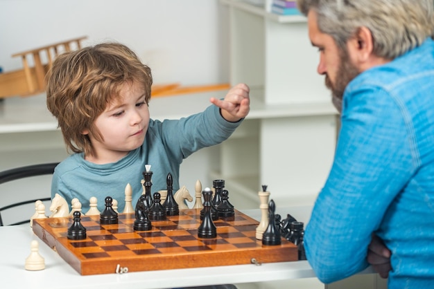 Pai com filho jogando xadrez em casa De volta à escola Pai ensinando seu filho a jogar xadrez