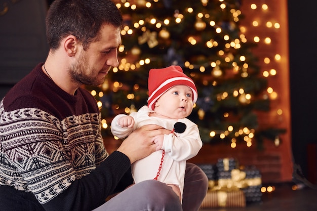 Pai com filho junto na sala decorada de Natal.