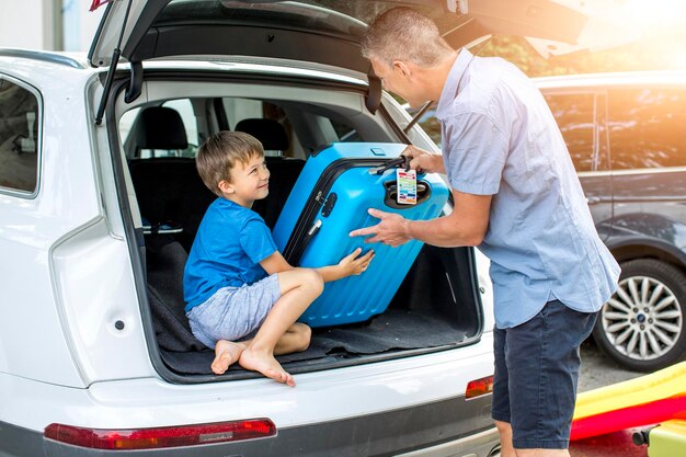 Foto pai com filho mantendo mala no carro