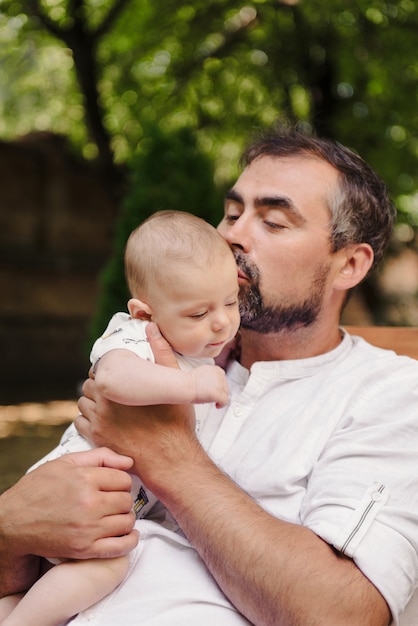 Pai com filho no parque enchendo simpático e terno, paternidade. Fofinho filho no colo do pai