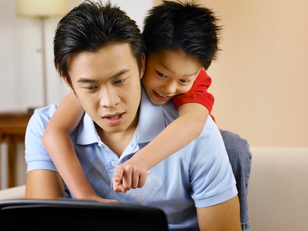 Pai com filho usando laptop em casa