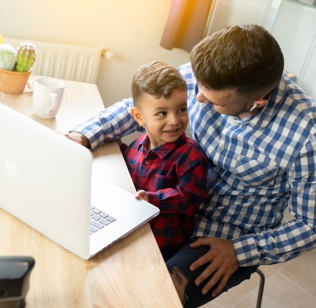 Foto pai com filho usando laptop em casa