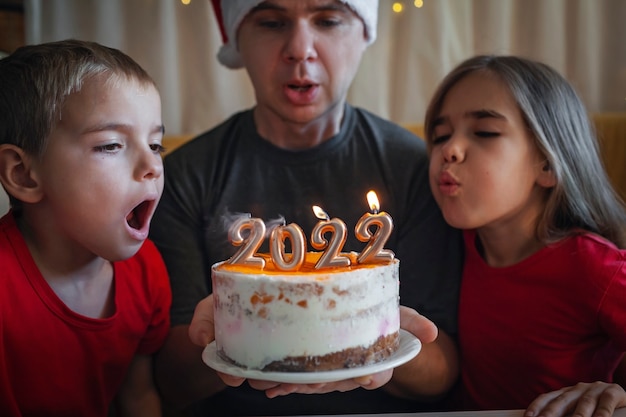 Pai com filhos antes do bolo de natal com fundo festivo de celebração de ano novo familiar de números