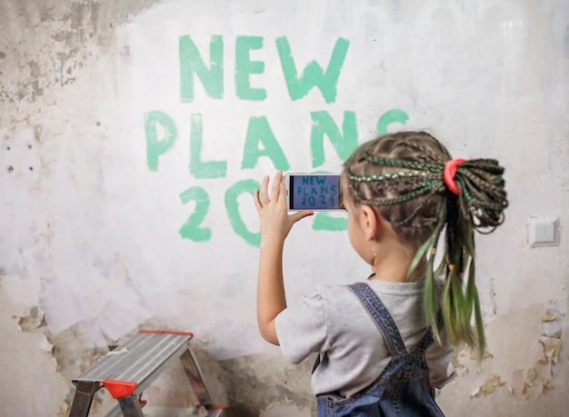 Foto pai com filhos planejando o ano novo com lista de verificação na parede e fazendo selfie com smartphone