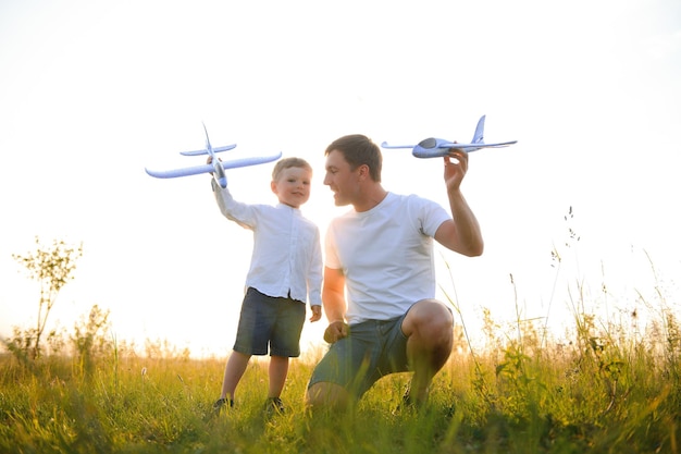 Pai com seu filho ao pôr do sol na natureza Um pai brinca com aviões de brinquedo com seu filho ao pôr do sol dia dos pais