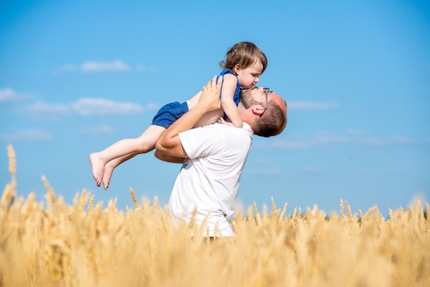 Foto pai com seu filho em um campo de trigo. pai e filho se divertindo ao ar livre no campo de trigo