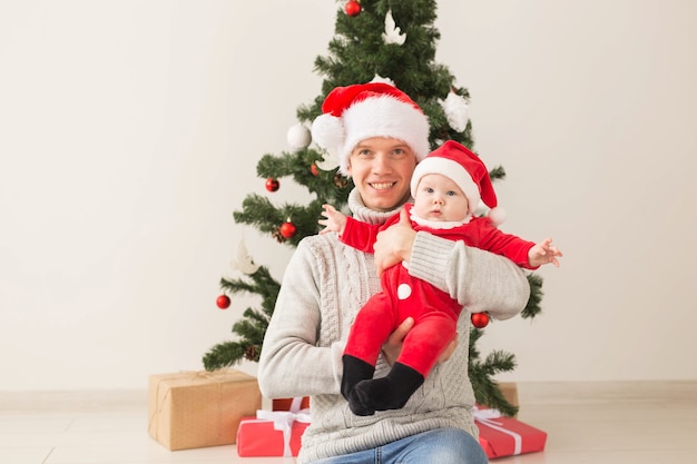 Pai com seu filho usando chapéus de Papai Noel, comemorando o Natal.