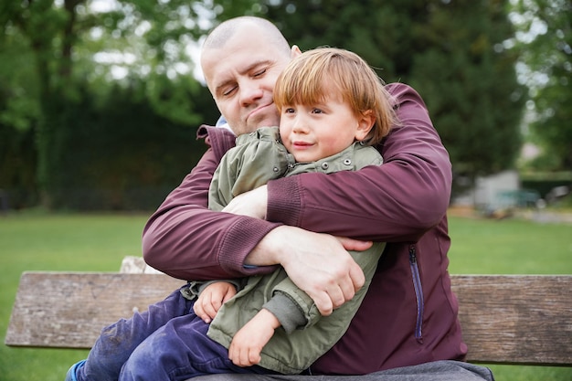 Pai consolando e abraçando filho chorando ao ar livre Conceito de paternidade pai confortando criança infeliz