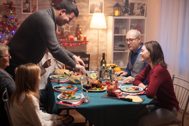 Pai cortando frango assado na festa de natal em família