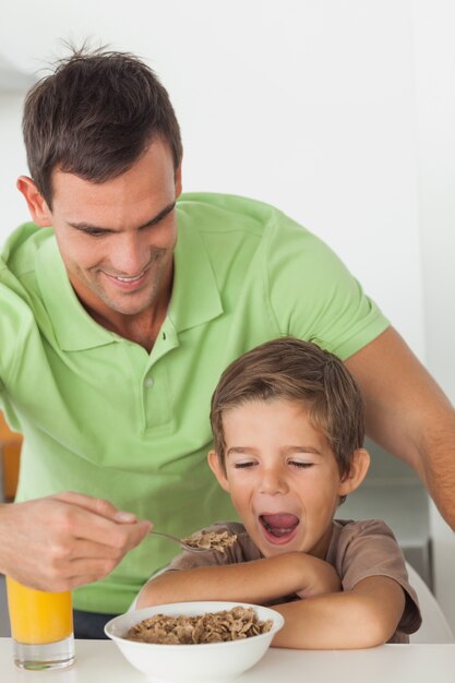 Pai dando cereal ao filho