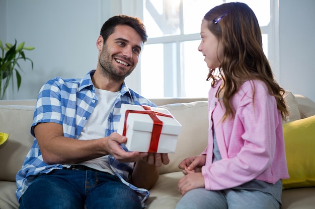 Pai dando presente para filha na sala de estar