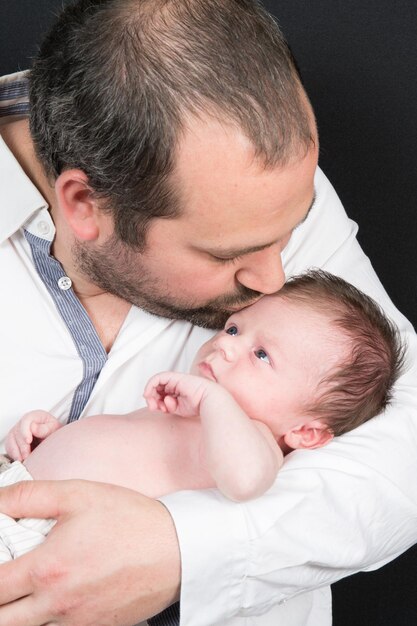 Pai de família faz um beijo para seu bebê recém-nascido