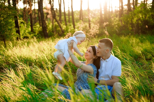 Foto pai de família feliz, mãe brincando ao ar livre no campo assistindo o belo pôr do sol emocional na luz de fundo