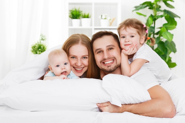 Pai de mãe de família feliz e dois filhos em casa na cama
