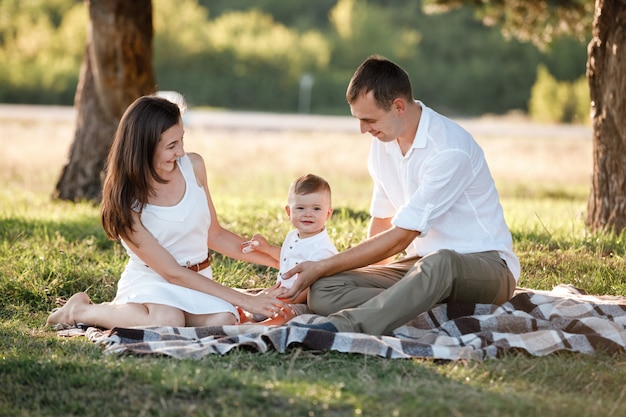 Pai de mãe de família feliz e filho bebê felizes na natureza, passando algum tempo juntos em um dia ensolarado de verão.