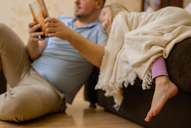 pai diverte a criança durante a doença ele olha lê um livro um livro de fotos com sua filha em casa