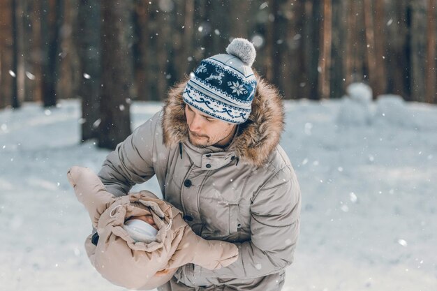 Pai e bebê estão andando pela floresta Pai segura um bebê nos braços no inverno Pai e filha ao ar livre no inverno