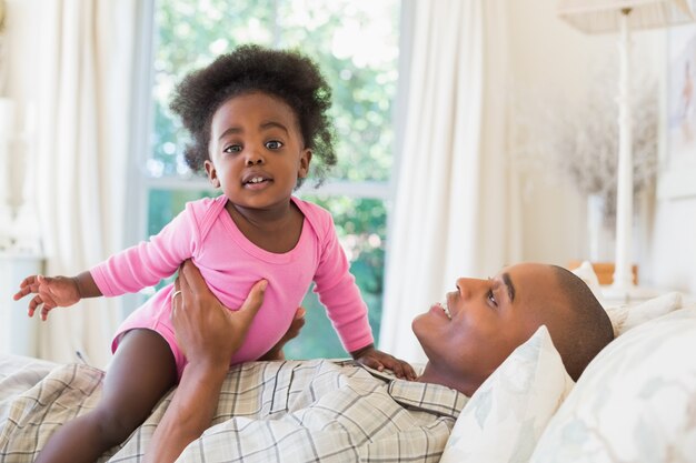 Pai e bebê menina deitada na cama juntos