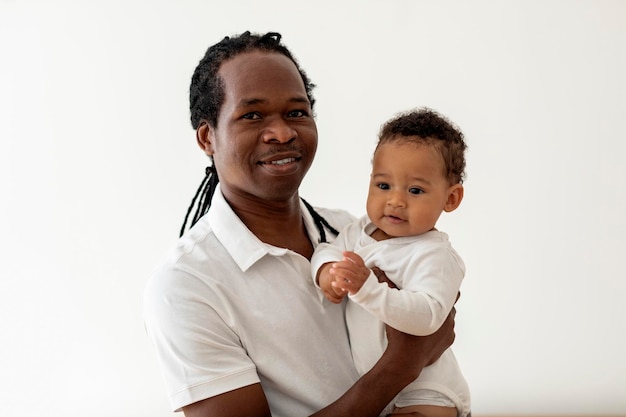 Foto pai e bebê pai negro posando com adorável criança nas mãos