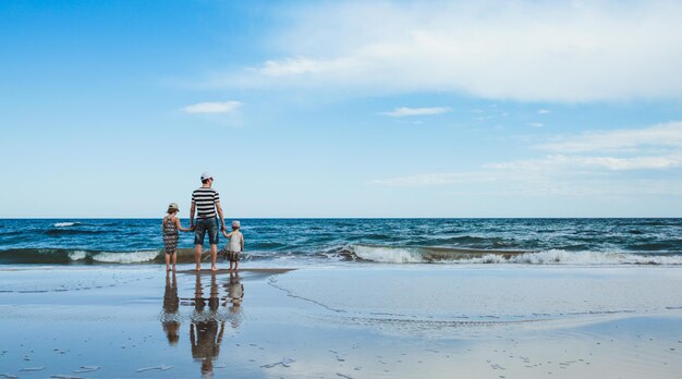 Pai e duas filhas em pé na praia