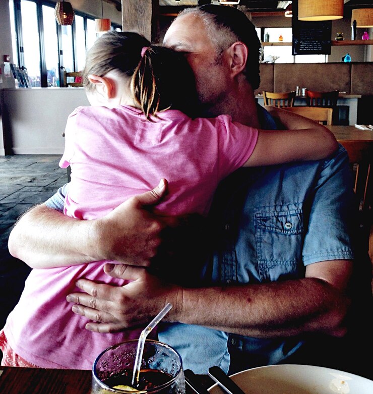 Foto pai e filha a abraçar-se num restaurante.