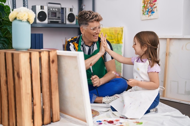 Pai e filha artistas high five com as mãos levantadas desenhando no estúdio de arte