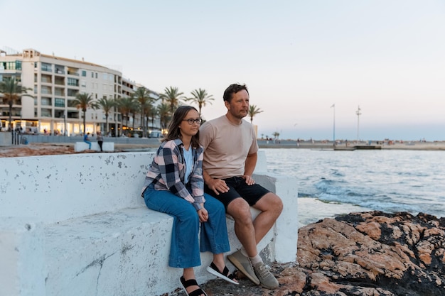 Pai e filha caminham à noite pela cidade à beira-mar