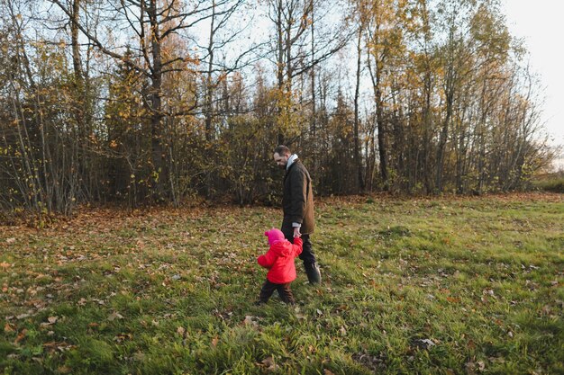 Pai e filha caminhando na floresta de outono