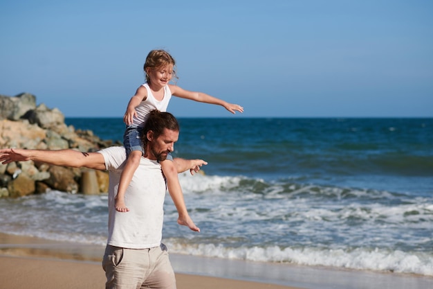 Pai e filha caminhando na praia