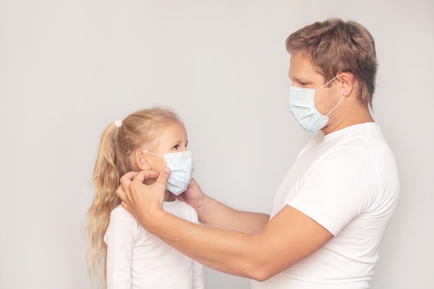 Pai e filha com máscaras médicas juntos em um fundo isolado.