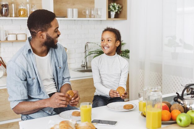 Pai e filha comendo biscoitos bebendo suco de laranja fresco