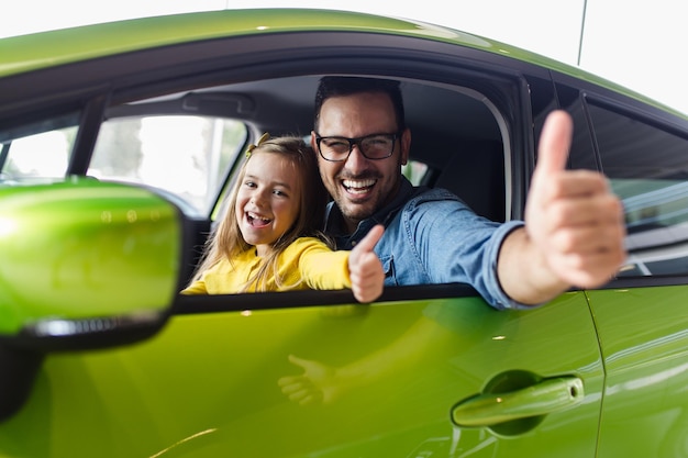 Foto pai e filha comprando um carro novo no showroom de carros.