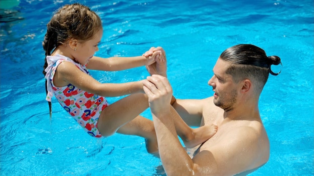 Pai e filha descansando e nadando em uma piscina no verão