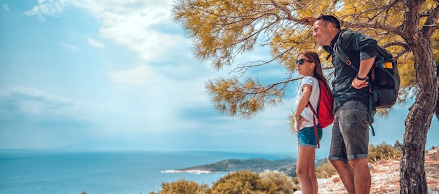 Pai e filha em pé em um penhasco à beira-mar