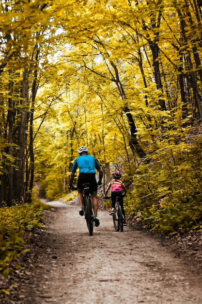 Pai e filha em um passeio de bicicleta em um fim de semana quente no início do outono.