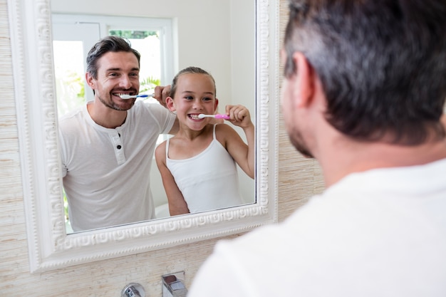 Pai e filha escovando os dentes no banheiro