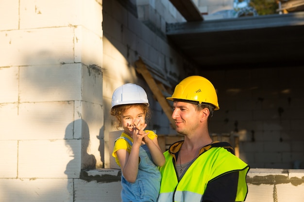 Pai e filha estão no canteiro de obras de sua futura casa. a escolha da futura profissão de construtor é herdada pela criança. a expectativa de mudança, o sonho de uma casa. empréstimo de hipoteca